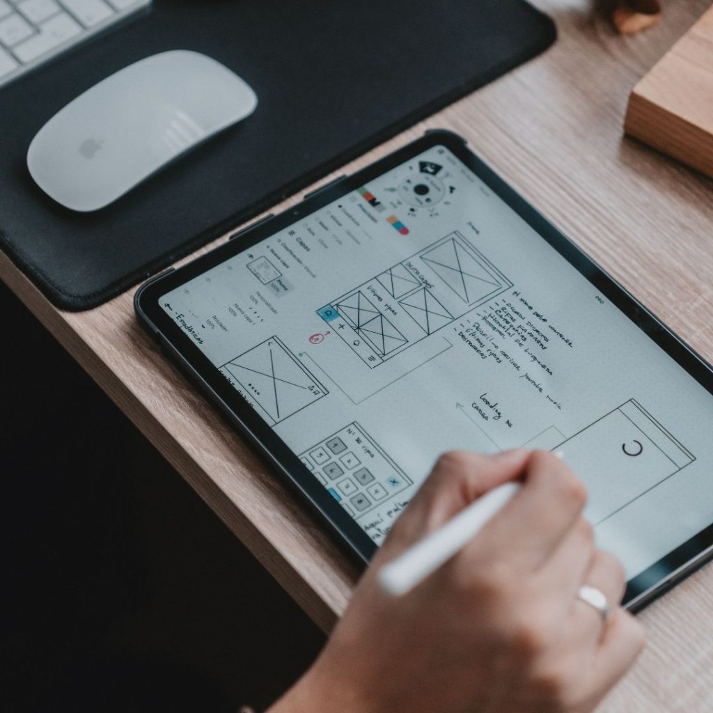 Designer sketching a wireframe on a tablet, showcasing UX/UI Design Principles in action.